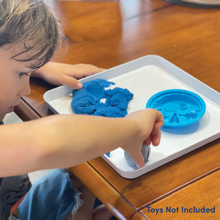 young child playing with play sand in the inside of one of the burner covers. sand not included
