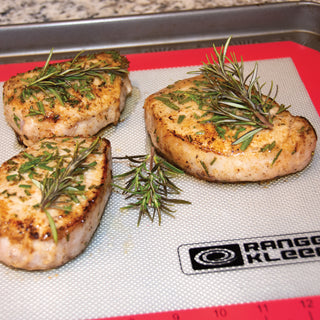 Grilled pork chops with rosemary on a silicone mat with 'Rangkleen' branding.