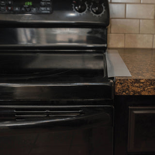Black oven in a kitchen setting with a tiled backsplash and granite countertop demonstrating the use of the kleen seam.