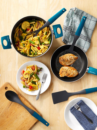 taste of home cookware and gadgets on wood table top with pasta and chicken