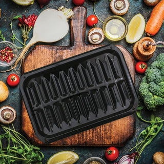 overhead of small broiler pan on cutting board with vegetables surrounding it on table