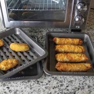 Two pans with food items on a countertop next to an oven.