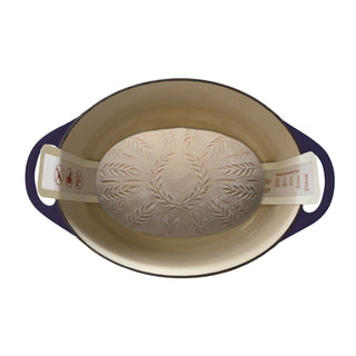 bread dough lowered into a hot cast iron dutch oven on white background ready to bake