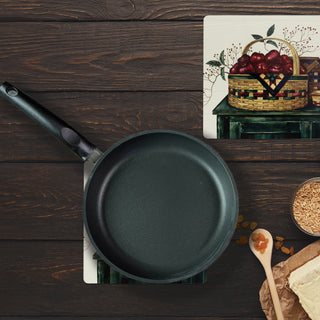 basket collection hot pad with skillet on top of it on table with raisins and wooden spoon and second hot pad sitting to side