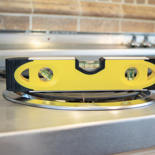 Yellow level on a stove top with a tiled wall background
