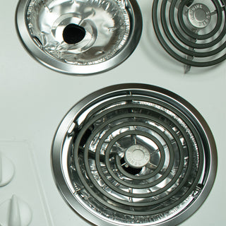 Close-up of two electric stove burners on a white background showing the placement of the electric foil liners in the drip bowls