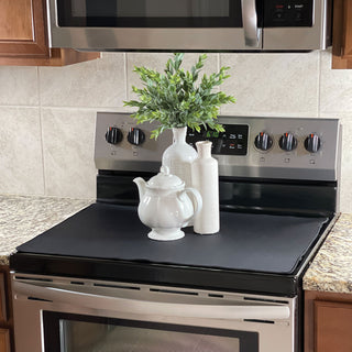 Stainless steel stove with black cooktop in a kitchen setting with mat in place and white vases on top of mat