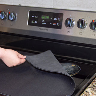 smooth top stove protector on stove with hand pulling back corner to show the scarred elements it can hide between stove uses