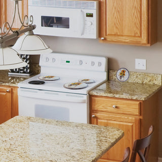 Kitchen with white stove, wooden cabinets, and granite countertops showing three Garden Harvest on stove top and one propped on side counter.