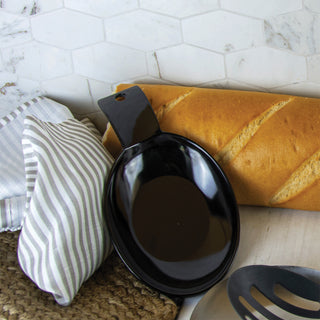 Black spoon rest, loaf of bread, and striped towel on a marble countertop