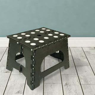 Black folding stool with white circular patterns on a light wooden floor and light blue wall background