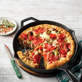 Pepperoni pizza in a Taste of Home Pre-Seasoned Cast Iron Skillet on a white surface with a checkered cloth.