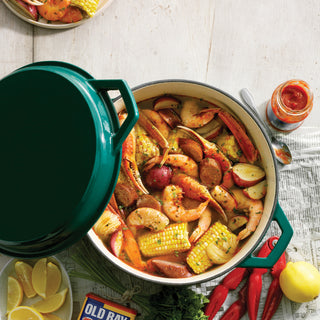 Taste of Home 7-Quart Enameled Cast Iron Dutch Oven with Grill Lid with shrimp, corn, carrots, and other vegetables on a table with seasonings.