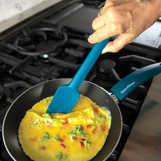 Person cooking an omelette in a Taste of Home Skillet with a Taste of Home Sea Green Spoonula on a stovetop.