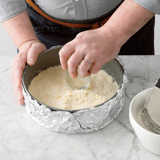 Person pressing a glass into a pie crust in a 9-Inch Non-Stick Metal Springform Baking Pan
